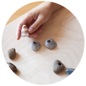 main qui tient une pierre avec plusieurs pierres posés sur une table